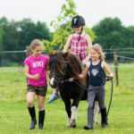 Drie meisjes waarvan een op een pony in een wei in Noord-Brabant
