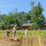 Drie kinderen spelend voor twee safaritenten in Noord-Brabant