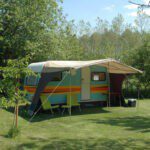 Kleurrijke caravan met luifel op een groen kampeerveld in Drenthe