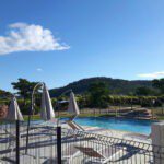 Zwembad met ligbedjes ernaast op Tendi Camping de L'Ovigne