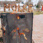 Vuurkorf met erachter het bord van vakantiepark Mölke