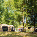 Beige tent op een groen kampeerveld aan de oever van rivier de Lot in Frankrijk