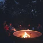 Mensen om een kampvuur op kleinschalige camping Tuin van Epicurus
