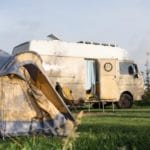 Camperbus met een tent ernaast op een kleinschalige camping in Zuid-Holland