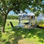 Caravan met luifel onder een boom op een kampeerveld in West-Friesland