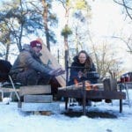 Man en vrouw bij een vuur op een besneeuwd natuurkampeerterrein in Overijssel