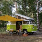 Groene VW camper met luifel en uitgeklapt dak op de Veluwe