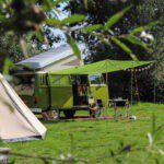 Hippiebusje op een groen kampeerveld in de Achterhoek