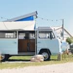 Blauwe Volkswagen camper met luifel en het dak uitgeklapt