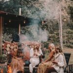 Vier vrouwen bij een vuur voor een houtstapel