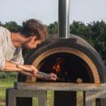 Man bij een steenoven pizza aan het bakken