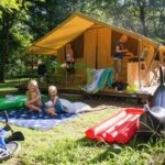 Safaritent met twee kinderen ervoor op Camping Huttopia Beaulieau Sur Dordogne