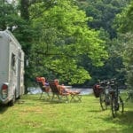 Caravan met twee mensen ervoor op een groene camping in de Dordogne