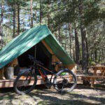 Ingerichte tent met fiets ervoor op Camping Huttopia La Clarée