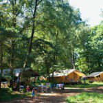 Safaritent omring door bomen op een Huttopia camping in Frankrijk