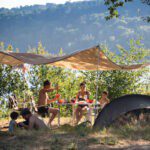Tent met luifel en een gezin eronder op Camping Huttopia Lac de la Siauve