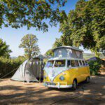 VW T1 camperbus met een tent ernaast op een kampeerveld in Frankrijk