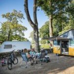 Volkswagen T2 camperbus met een caravan ernaast op een kampeerveld in Frankrijk