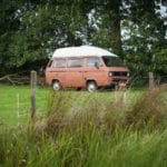 Oranje VW T3 rijdt op het platteland