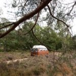 Oranje volkswagen T3 rijdt door de natuur