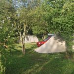 Twee beige tenten tussen de bomen op een groene camping in Frankrijk