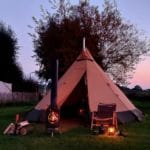 Ingerichte tent met een houtkachel op camping Oosterbeeks Rijnoever