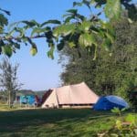 Blauwe en beige tent op een groen kampeerveld in Frankrijk