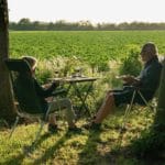 Twee personen zitten aan een tafel en kijken uit op het Drentse platteland