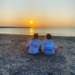 Twee meisjes kijken naar de zonsondergang boven de Noordzee
