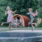 Kinderen springen op een trampoline voor een Pod op Camping Zwinderen