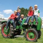 Vijf kinderen op een traktor op boerderijcamping De Steenuil in Brabant