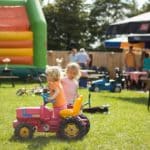 Twee kinderen met een speelgoed traktor op Camping en speelboerderij de Steenuil
